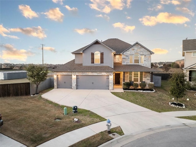 traditional home with stone siding, concrete driveway, a garage, and fence