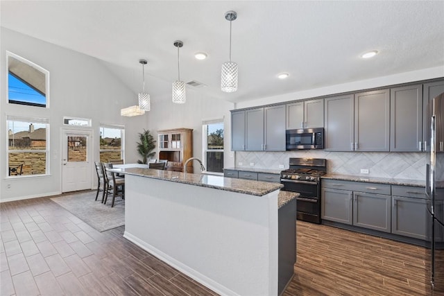 kitchen featuring gray cabinetry, light stone countertops, backsplash, and stainless steel appliances