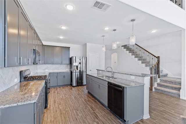 kitchen featuring a sink, stainless steel appliances, wood finished floors, and gray cabinets