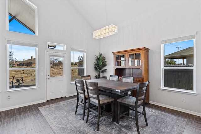 dining area with a notable chandelier, baseboards, high vaulted ceiling, and wood finished floors