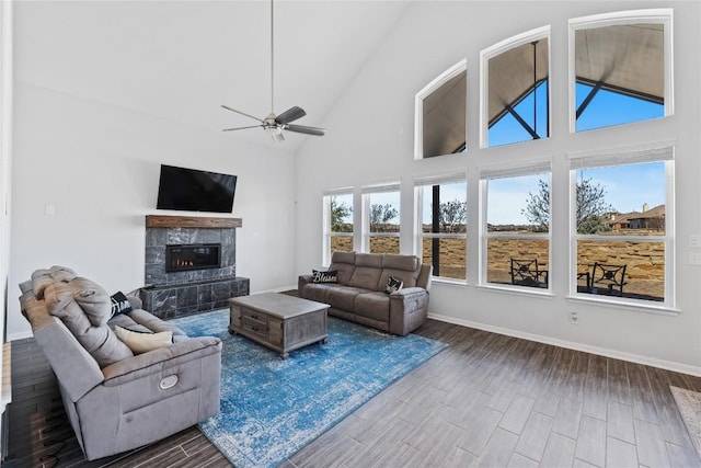 living area with baseboards, high vaulted ceiling, dark wood-style flooring, and a tile fireplace