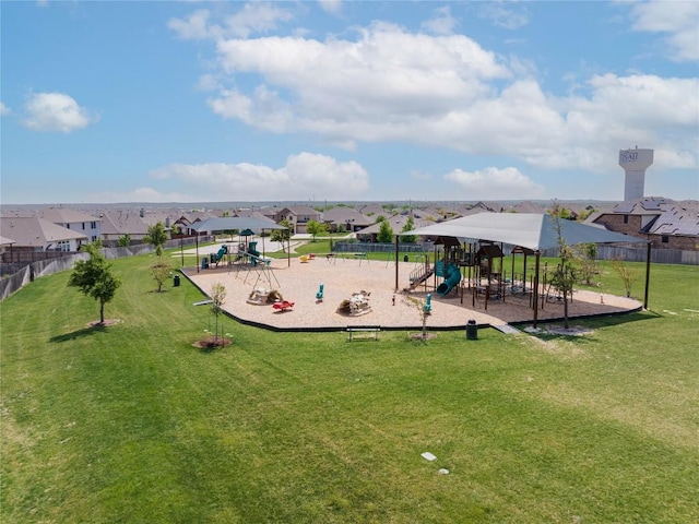 communal playground featuring a yard, fence, and a residential view