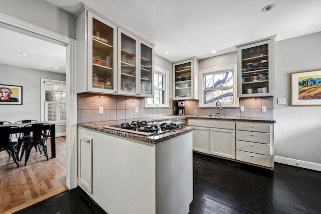 kitchen featuring a sink, dark wood finished floors, dark stone countertops, and gas stovetop