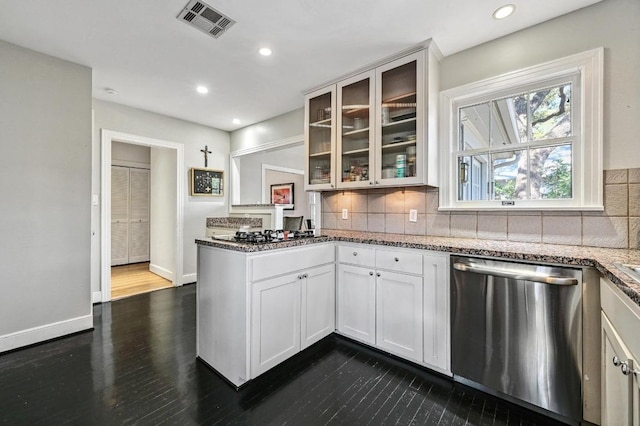 kitchen featuring stainless steel dishwasher, glass insert cabinets, visible vents, and backsplash