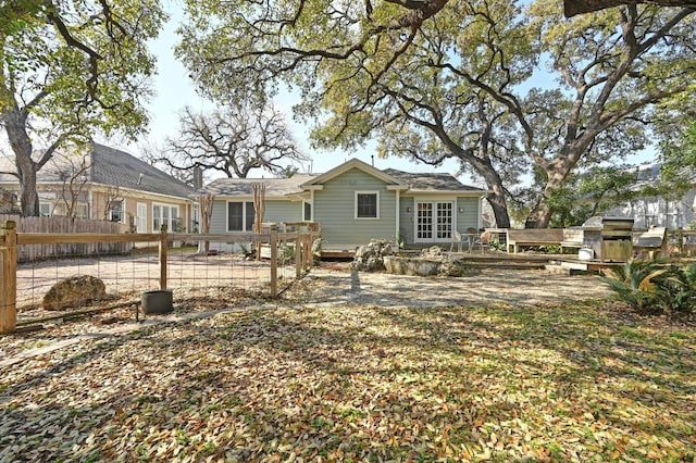 back of property featuring french doors, a wooden deck, and fence