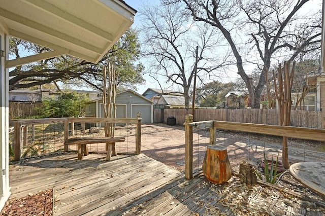 wooden deck featuring an outbuilding, a detached garage, and a fenced backyard