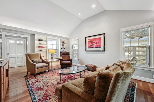 living room featuring plenty of natural light, baseboards, light wood-type flooring, and lofted ceiling