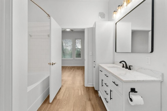 full bath with vanity, shower / bathing tub combination, wood finished floors, and baseboards