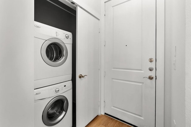 washroom featuring light wood-type flooring, stacked washer / drying machine, and laundry area