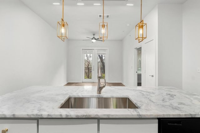 kitchen with visible vents, a sink, open floor plan, light stone countertops, and dishwasher