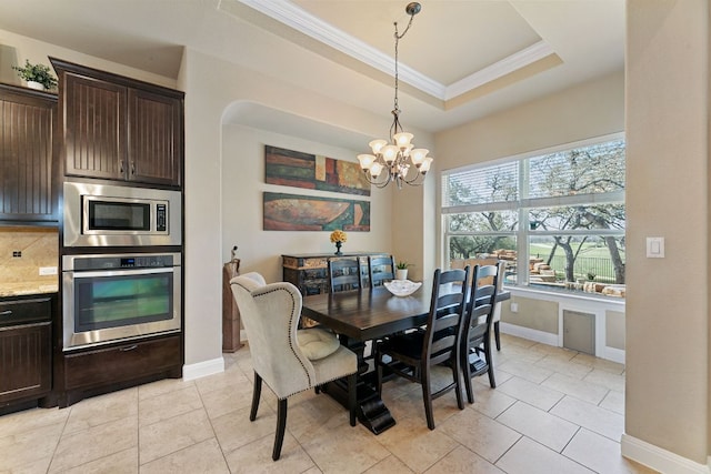 dining room with a tray ceiling, crown molding, light tile patterned floors, baseboards, and a chandelier