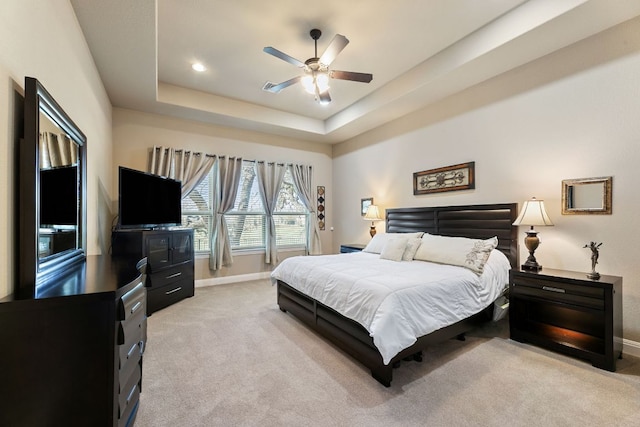 bedroom with a tray ceiling, baseboards, light colored carpet, and ceiling fan