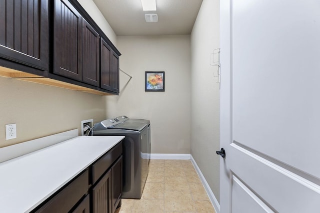 clothes washing area featuring baseboards, cabinet space, and washing machine and clothes dryer