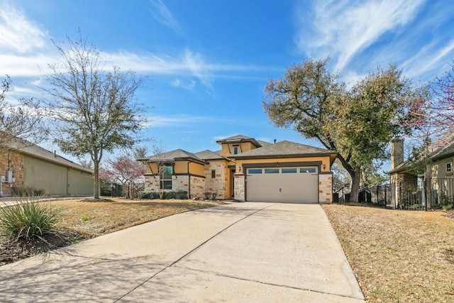 prairie-style house with fence, stucco siding, concrete driveway, a garage, and stone siding