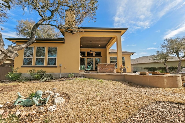 rear view of house featuring a patio, a ceiling fan, fence, an outdoor kitchen, and stucco siding