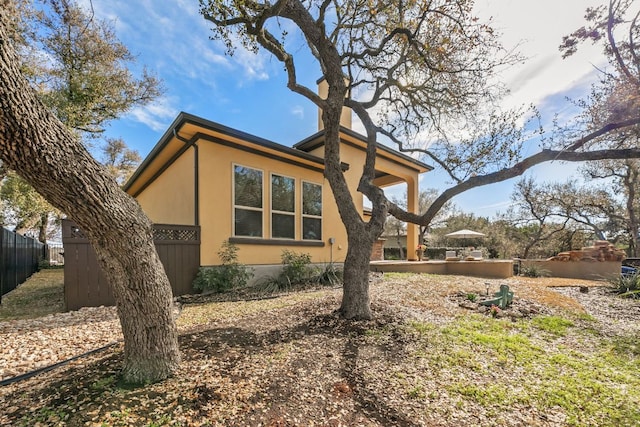 view of property exterior with fence and stucco siding