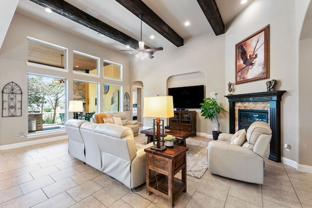 living area featuring a ceiling fan, baseboards, light tile patterned flooring, a fireplace, and arched walkways