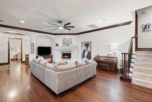 living room featuring dark wood finished floors, visible vents, crown molding, and ceiling fan