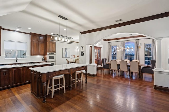 kitchen with light countertops, a notable chandelier, arched walkways, and ornate columns