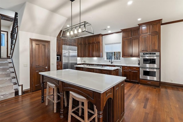 kitchen with dark wood-style floors, appliances with stainless steel finishes, a center island, and light countertops