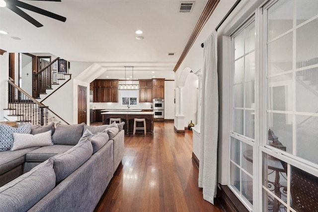 living room featuring visible vents, stairs, dark wood-type flooring, and a ceiling fan