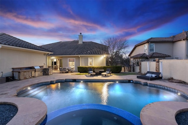 view of pool featuring an outdoor kitchen, a pool with connected hot tub, a patio, and fence