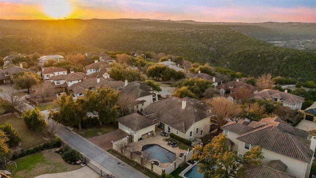 aerial view at dusk featuring a mountain view and a residential view