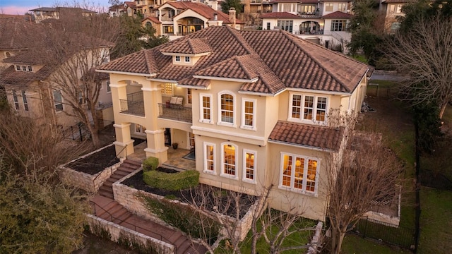 back of house with stairway, stucco siding, a tile roof, and a balcony