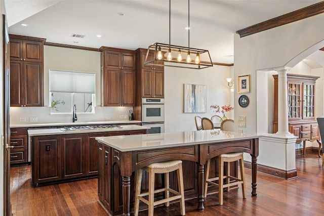 12027 Pleasant Panorama Vw, Austin, TX 78738 - kitchen featuring a center island, decorative columns, ornamental molding, dark wood finished floors, and light countertops