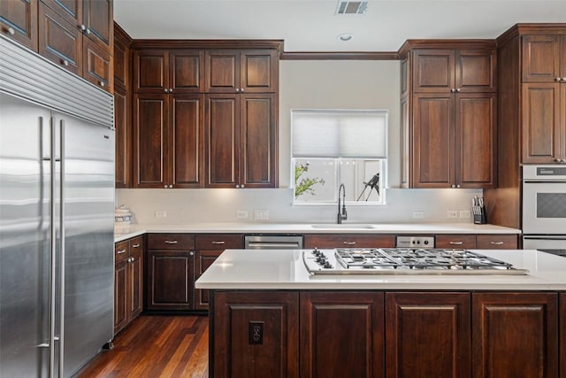 12027 Pleasant Panorama Vw, Austin, TX 78738 - kitchen with appliances with stainless steel finishes, light countertops, dark wood-style flooring, and dark brown cabinetry