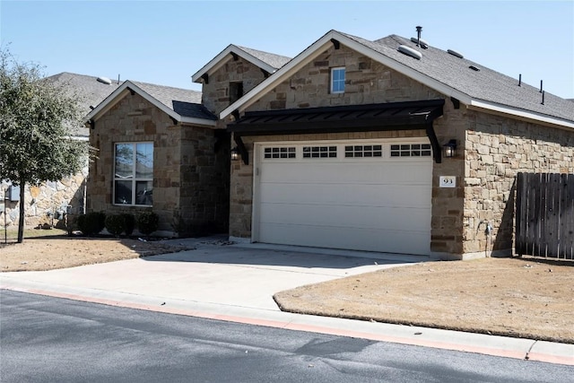 view of front of house featuring driveway, stone siding, fence, roof with shingles, and an attached garage