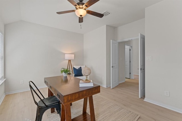 home office featuring light wood finished floors, visible vents, baseboards, lofted ceiling, and a ceiling fan