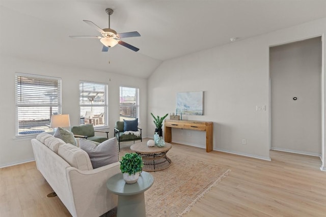 living room featuring baseboards, lofted ceiling, light wood-style floors, and a ceiling fan