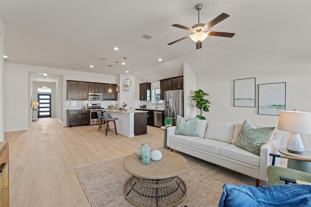 living room featuring visible vents, lofted ceiling, recessed lighting, light wood-style flooring, and a ceiling fan