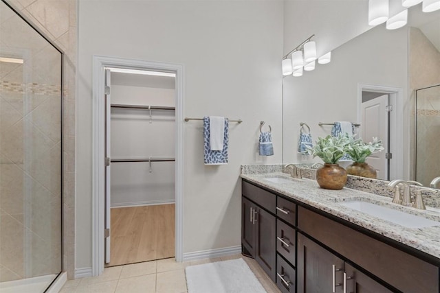 full bathroom featuring a spacious closet, tile patterned flooring, a shower stall, and a sink