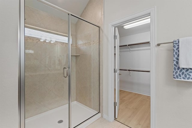 bathroom featuring a walk in closet and a shower stall