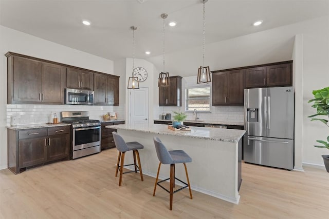 kitchen featuring stainless steel appliances, dark brown cabinets, a breakfast bar area, and a center island