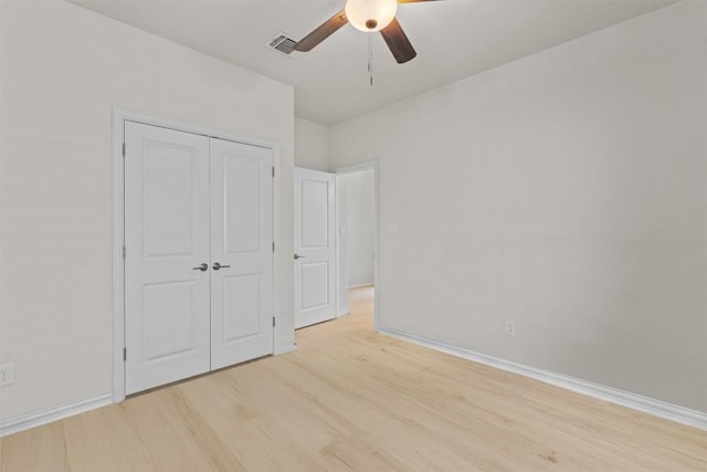 unfurnished bedroom with baseboards, visible vents, light wood finished floors, ceiling fan, and a closet