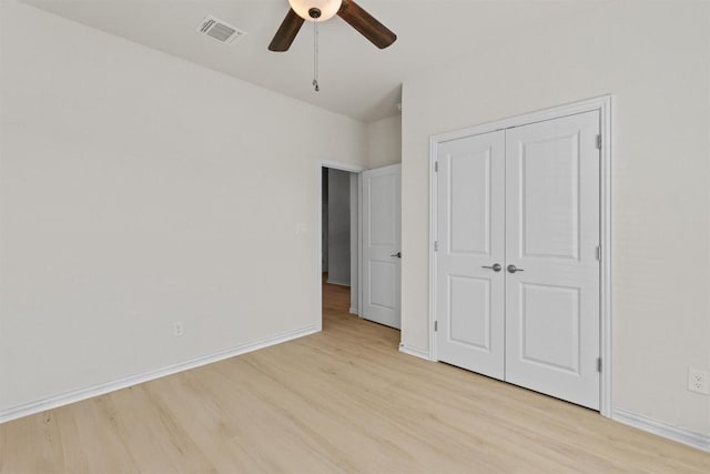 unfurnished bedroom featuring light wood finished floors, visible vents, ceiling fan, baseboards, and a closet