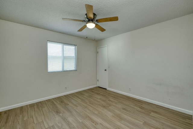 spare room with a textured ceiling, a ceiling fan, light wood-type flooring, and baseboards