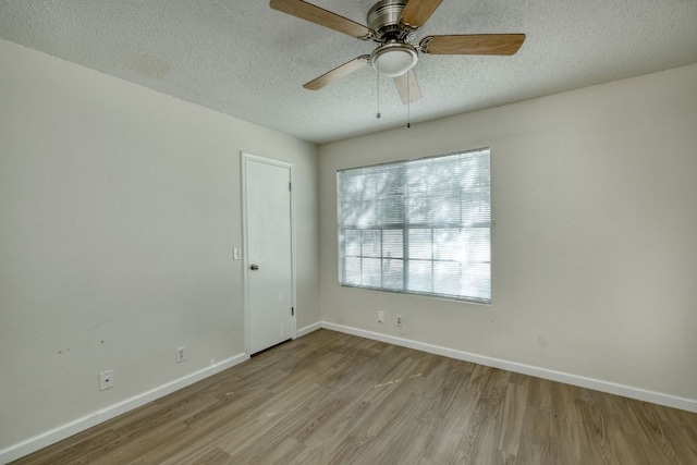 unfurnished room with ceiling fan, a textured ceiling, baseboards, and wood finished floors