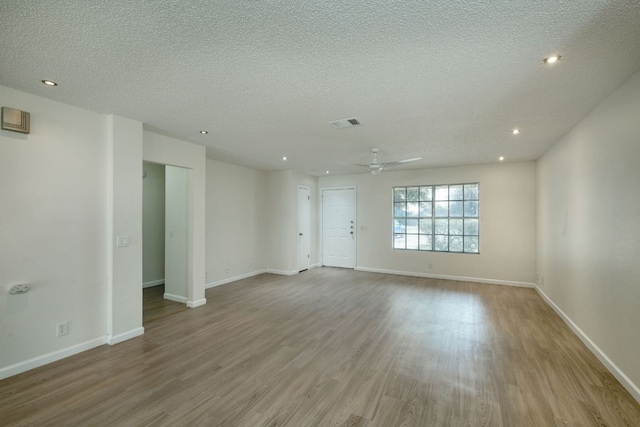 unfurnished living room with visible vents, baseboards, ceiling fan, wood finished floors, and a textured ceiling