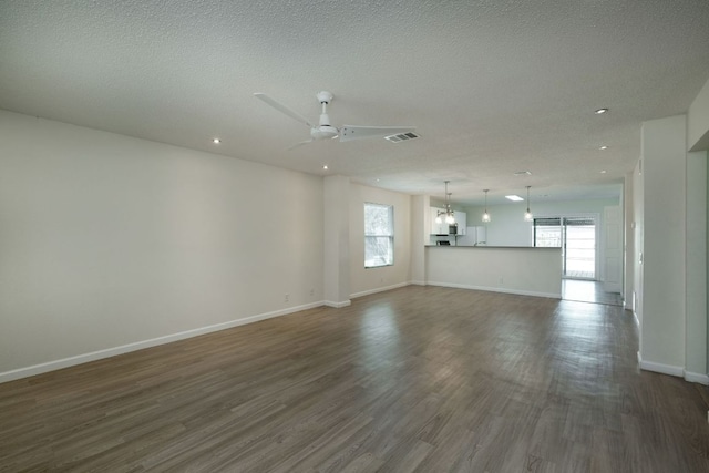 unfurnished living room with visible vents, a ceiling fan, a textured ceiling, dark wood finished floors, and baseboards