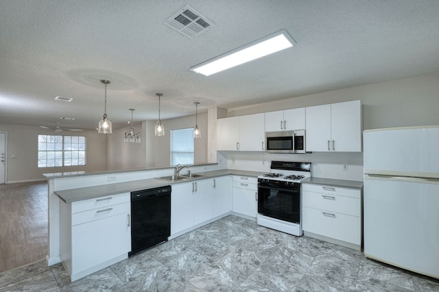 kitchen with stainless steel microwave, visible vents, gas range, black dishwasher, and freestanding refrigerator