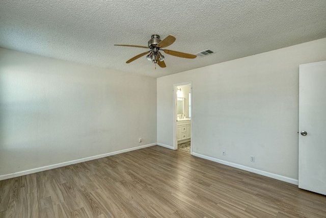 unfurnished room featuring visible vents, baseboards, wood finished floors, a textured ceiling, and a ceiling fan