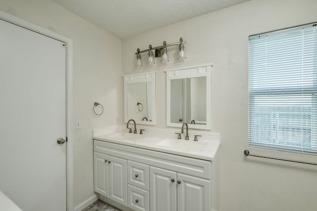 full bathroom featuring a textured ceiling, double vanity, and a sink