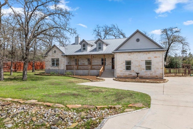 view of front of property with a front lawn, stone siding, a porch, fence, and concrete driveway