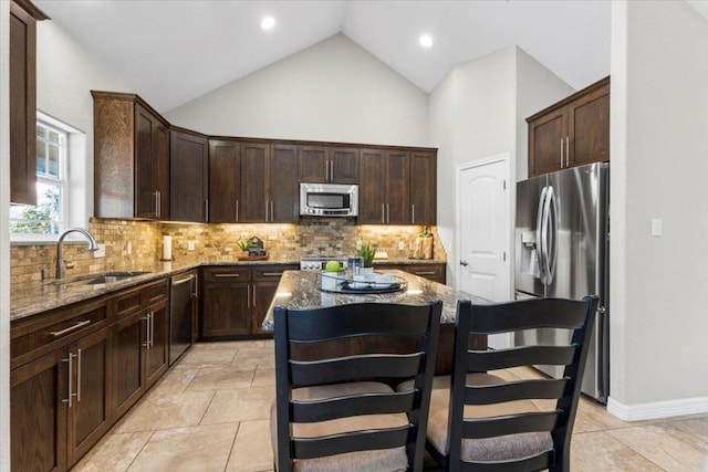 kitchen featuring a sink, light stone countertops, a kitchen island, and stainless steel appliances