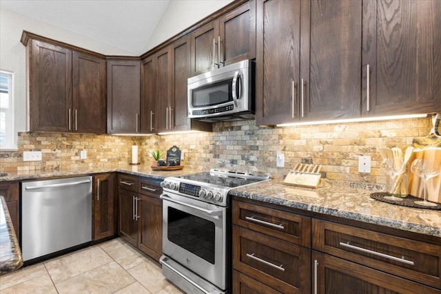 kitchen with light stone counters, light tile patterned floors, vaulted ceiling, appliances with stainless steel finishes, and backsplash