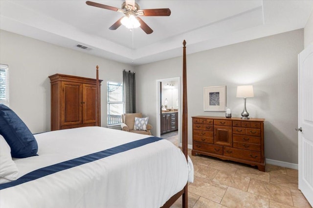 bedroom with baseboards, visible vents, ceiling fan, a raised ceiling, and connected bathroom